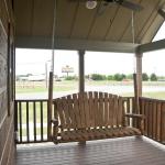 Front porch swing on the Platinum model P-528FPSP (Meadowview) with Chinked Log accents on display at Recreational Resort Cottages and Cabins in Rockwall, Texas.  